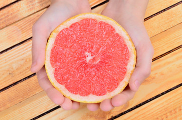 hand hold a half of grapefruit on table