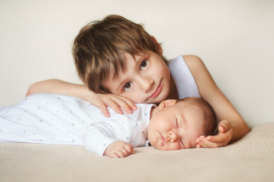 Older Brother Hugging Newborn Baby