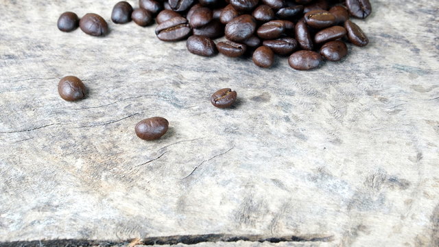 Dark roasting coffee beans on a wood table.