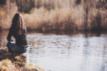 Girl sitting on a rock on the Bank of river forest