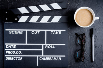 Screenwriter desktop with movie clapper board dark background top view