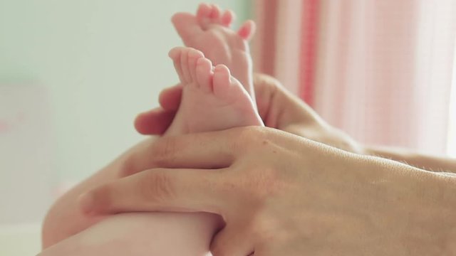 Mother gently caresses feet of infant in crib 100p slomo.Close up of the hands of the mother gently and with great affection caressing the feet of her baby at home.