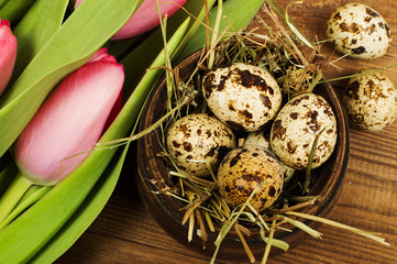 Obraz premium Chicken and quail eggs with tulips. Easter background