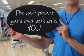 Personal fitness trainer holding workout inspiration motivation quote on blackboard.