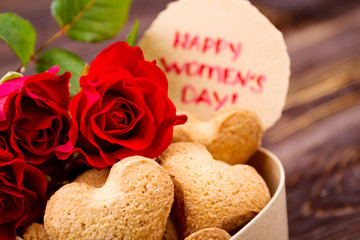 Obraz na płótnie Canvas Women`s Day card and cookies. Heart-shaped biscuits and roses. Cooking for women. Day of pleasant gifts.