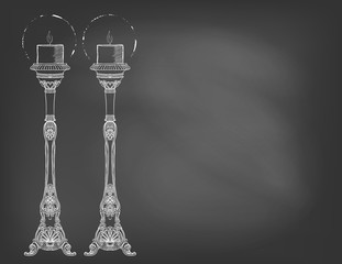 Two highly ornamental candles on chalkboard