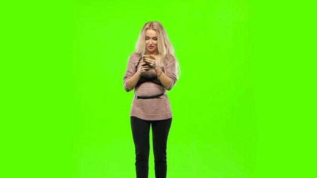 Girl blonde goes and look at your phone. Green screen