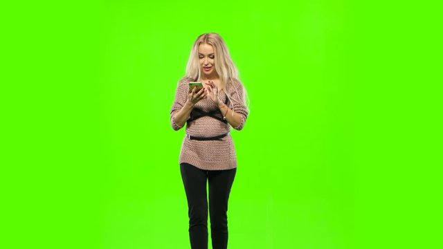 Girl blonde goes and look at your phone. Green screen