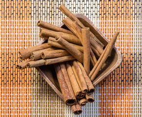 Oriental fragrant cinnamon sticks in wooden bowl