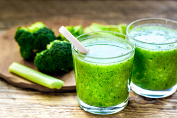 Green vegetable smoothie in glass at wooden background