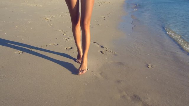 Female Legs Walking along the Beach at Sunset