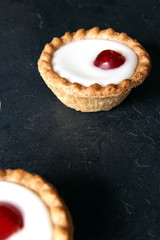 Cherry bakewell tarts on dark background