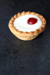 Cherry bakewell tart on dark background