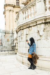Fototapeta na wymiar Young woman taking a selfie photo in front of the the Renaissance Cathedral in Malaga, Andalusia, Spain