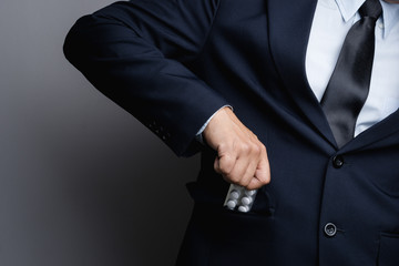 Business man hand holding white medicine pills in blister pack