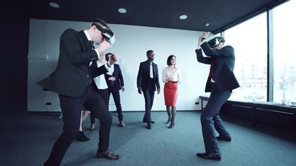 Two businessmen trying on helmets of virtual reality during the meeting. Their start to fight in vr headsets opposite colleagues in office. - Powered by Adobe