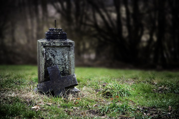 Broken stone cross, weathered gravestone on an old abandoned cementery, halloween symbol