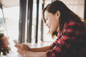 Close up of woman smiling while holding cell phone and texing.