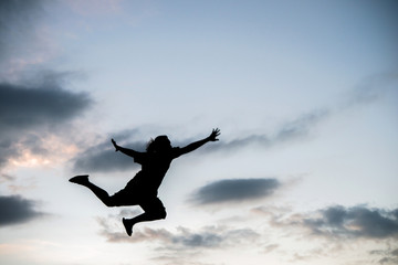Fototapeta na wymiar Happy young woman jumping against beautiful sunset. Freedom,