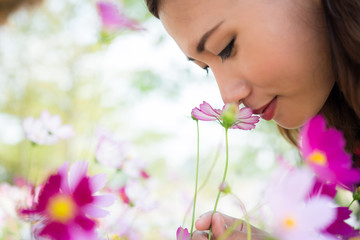 Close up of cheerful woman smelling with cosmos flower at garden