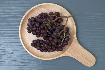 Fresh colorful healthy organic seedless red grapes gruits on wood dish.