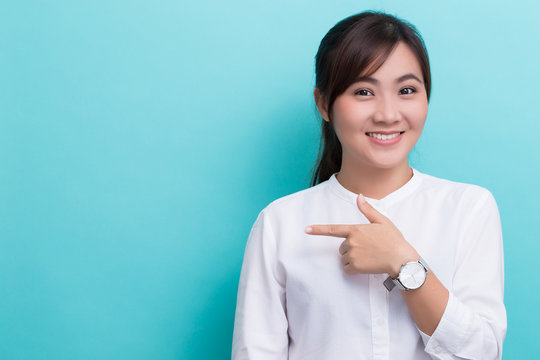 Asian woman pointing to the copy space isolated on blue backgrou