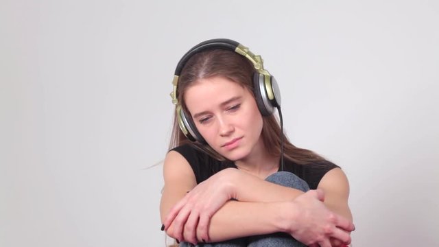 Woman sad unhappy girl in big headphones listening music. Broken heart love concept