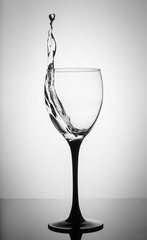 Water splashing in wine glass on white background