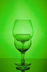 Two empty wine glass on green background
