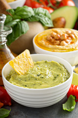 Guacamole and hummus in white bowls