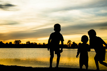 A silhouette of a happy family of four people, baby, and child, and their dog in front of a sunsetting sky, with room four copy space or text