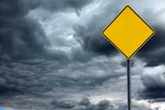 blank road warning sign in front of storm cloud background, ready for text