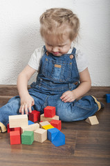 Little cute girl playing with a wooden constructor