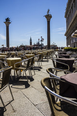 Street cafe waiting for tourist at San Marco square with view  of San Marco and San Todaro columns in Venice, Italy