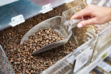 Buyer with scoop takes pine nuts in store