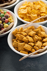 Variety of cold cereals in white bowls with spoons