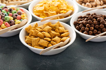 Variety of cold cereals in white bowls with spoons