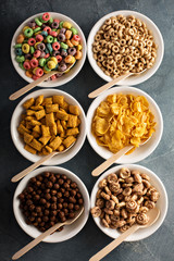Variety of cold cereals in white bowls with spoons
