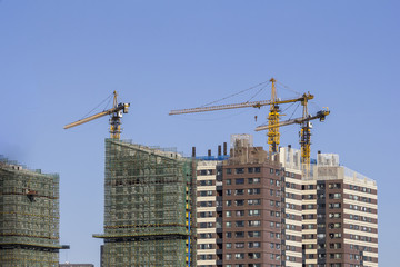 Fototapeta na wymiar Three cranes working on top of a building in China