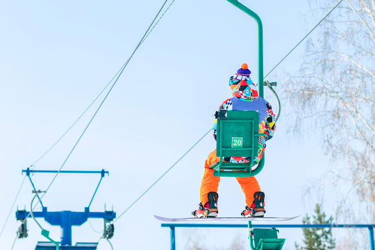 Snowboarder rises to the chairlift to the track