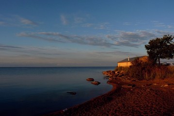 house on the beach with a tree at sunset