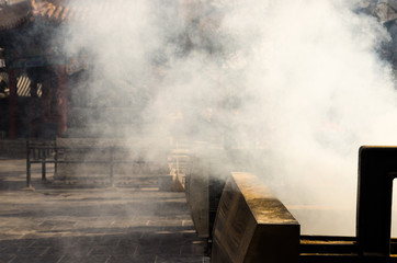 The smoke from the joss stick in the pot