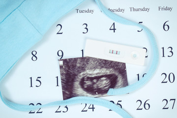 Vintage photo, Pregnancy test, ultrasound scan of baby and clothing for newborn on calendar, expecting for baby