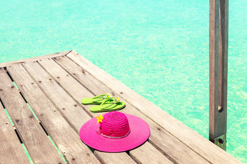 Large pink sun hat and sandal on the deck by the sea
