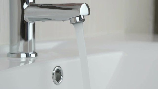 Male hands opening chrome-plated tap for washing hands