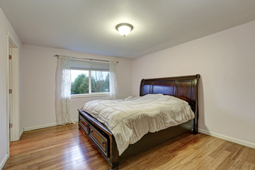 White bedroom with dark stained wood bed with lower drawers