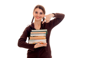 happy young brunette student girl in brown sport clothes with a lot of books in her hands smiling on camera isolated on white background