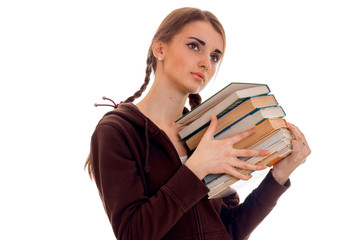 tired young brunette student girl in brown sport clothes with a lot of books in her hands posing isolated on white background