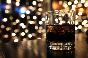 glass of alcohol with ice on blured background with circle bokeh