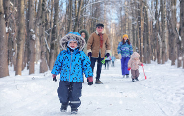 Kid playing in a winter park and have fun with family